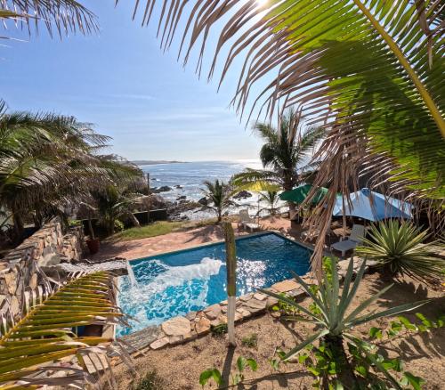 una piscina con palme e vista sull'oceano di Hotel Luz de Mar ' right on the beach a Cuatunalco