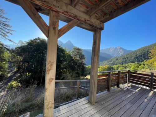 une terrasse en bois avec vue sur les montagnes dans l'établissement Les 2 louveteaux, à Uvernet