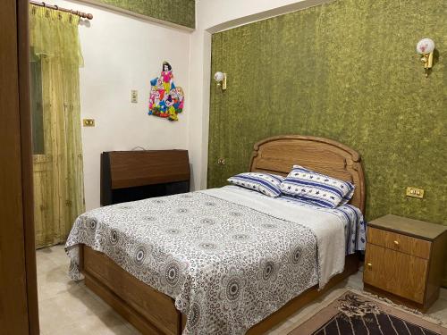 a bedroom with a bed and a green wall at Dr milad shokralla multiple central flats in Luxor