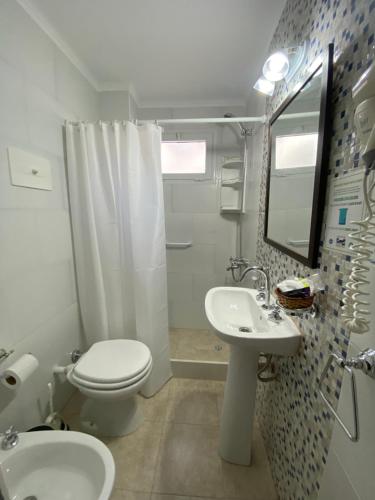a bathroom with a white toilet and a sink at Lugra Hotel in Miramar