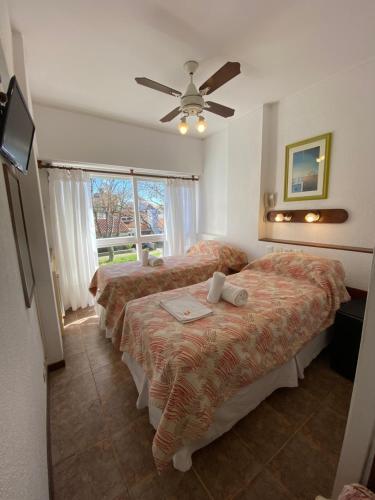a bedroom with two beds and a window and a ceiling fan at Lugra Hotel in Miramar