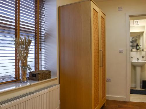 a bathroom with a wooden cabinet next to a window at Walnuts Nest in Minehead