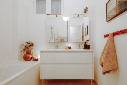 une salle de bain blanche avec un lavabo et un miroir dans l'établissement Royo - 1 chambre à Auteuil, à Paris