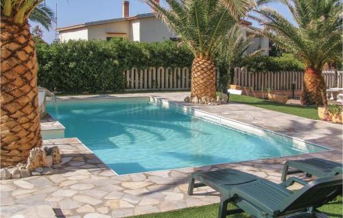 een zwembad met 2 stoelen en palmbomen bij Nice Apartment In Valledoria With Outdoor Swimming Pool And 1 Bedrooms in Valledoria