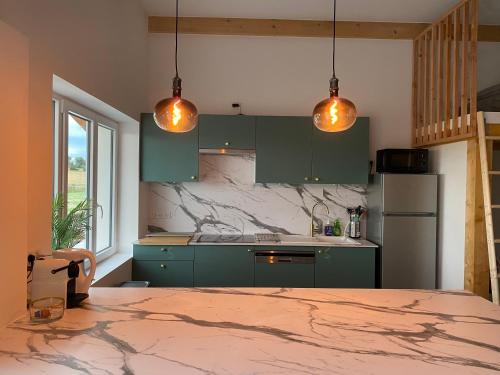 - une cuisine avec des placards verts et 2 lampes suspendues dans l'établissement Domaine Font Castel - Gîte Ottignies, à Béziers
