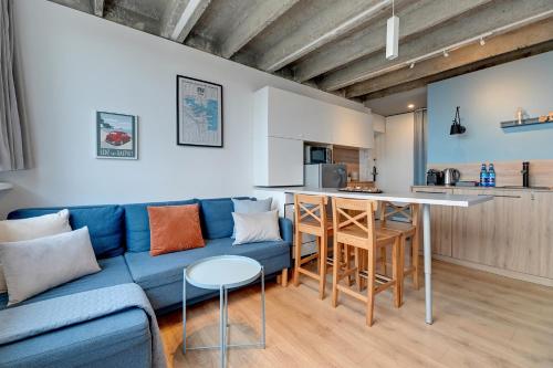 a living room with a blue couch and a kitchen at Gdynia z widokiem na morze by Downtown Apartments in Gdynia
