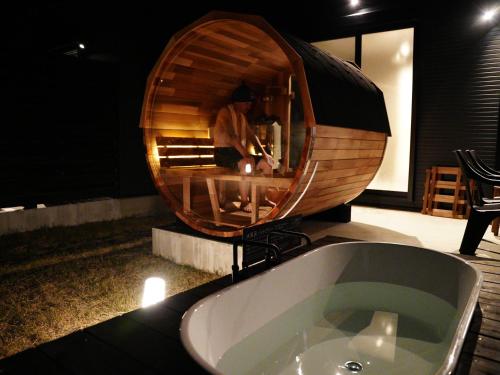 a bath tub in a bathroom with a round mirror at SAKURA YAKUSHIMA in Yakushima