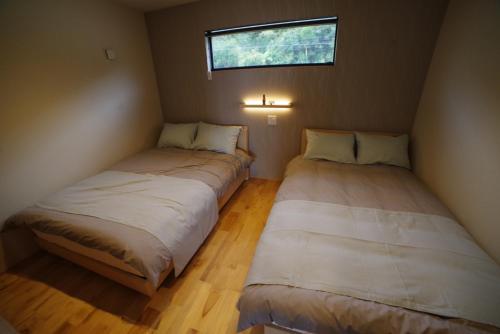 twee bedden in een kleine kamer met een raam bij SAKURA YAKUSHIMA in Yakushima