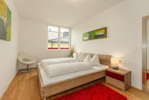 シュラートミンクにあるAppartements Tamino by Schladming-Appartementsのベッドルーム(赤い敷物付きの白い大型ベッド1台付)
