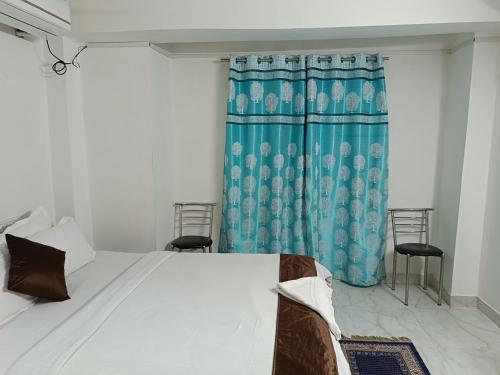 a bedroom with a bed and a blue curtain at HOTEL ATITHI GRAND in Guwahati