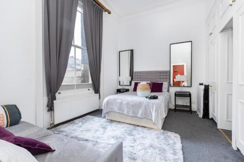 a white bedroom with two beds and a window at Harrods Flats in London
