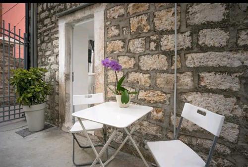 a white table and two chairs in front of a brick wall at Apartments Lotti 2 in Stari Grad