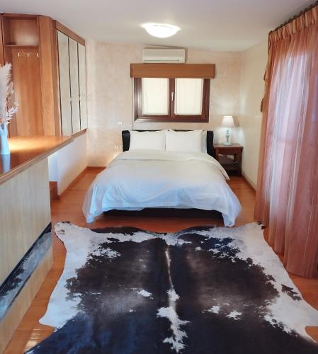 a bedroom with a white bed and a black rug at sunlight loft in Kastoria