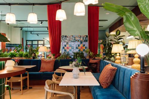 a restaurant with blue couches and tables and plants at room2 Belfast Hometel in Belfast