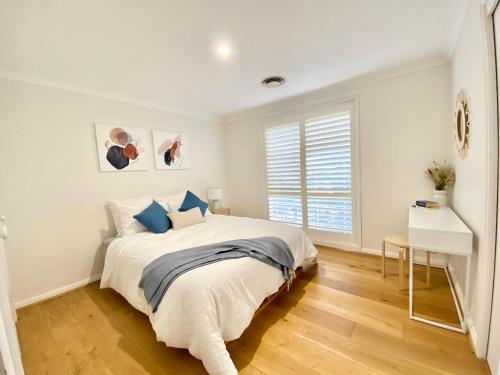 a white bedroom with a bed and a window at Cosy 3BR House, 7 mins drive to Macquarie Centre, 5 stars on AirB&B in Sydney
