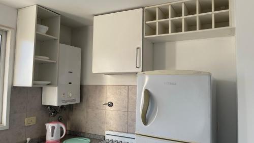 Una cocina con gabinetes blancos y un refrigerador. en Ruffus´s Apple Rosario, en Rosario