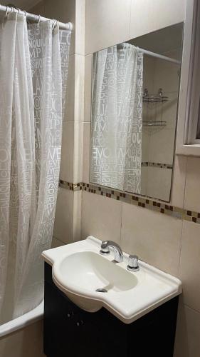 a bathroom with a sink and a shower curtain at Ruffus´s Apple Rosario in Rosario