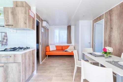 an apartment kitchen with an orange couch in the background at San Benedetto Camping Relais in Peschiera del Garda