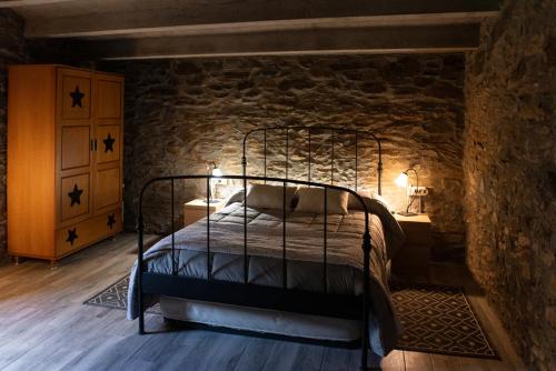 ein Schlafzimmer mit einem Metallbett in einer Steinmauer in der Unterkunft Masia Casa Nova de n'Illa in Montseny