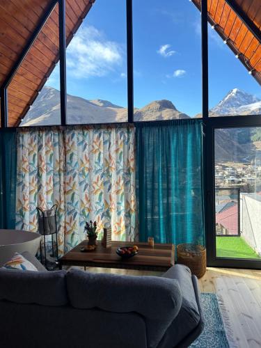 a living room with a couch and large windows at Cottage Veranda in Kazbegi