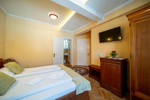 a bedroom with two beds and a tv on the wall at Lilla Panzió in Odorheiu Secuiesc