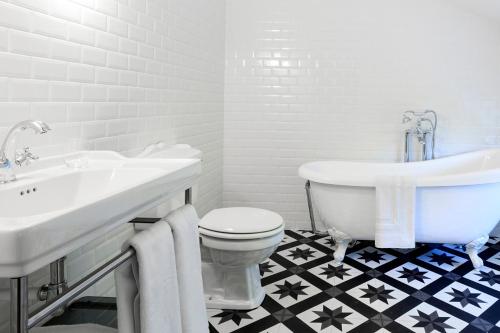 een badkamer met een bad, een toilet en een wastafel bij L’Auberge du Château in Dampierre