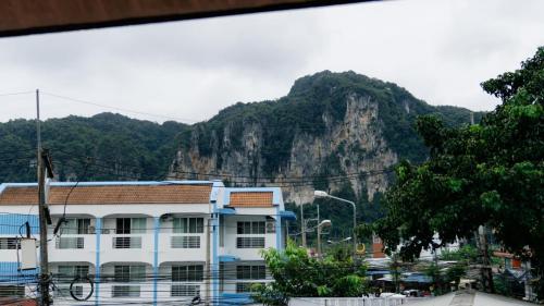 a white building with a mountain in the background at Aonang Knockout Hostel in Ao Nang Beach