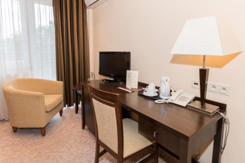 a hotel room with a desk with a lamp and a chair at Hotel Kudowa Manufaktura Relaksu in Kudowa-Zdrój