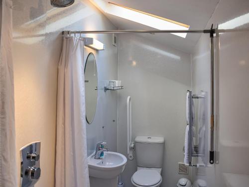 La salle de bains blanche est pourvue de toilettes et d'un lavabo. dans l'établissement Allerton House Stable, à Jedburgh