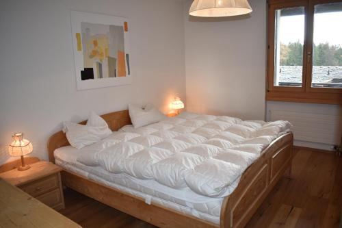 een groot bed in een kamer met een raam bij Bella Val (272 Pe) in Lenzerheide