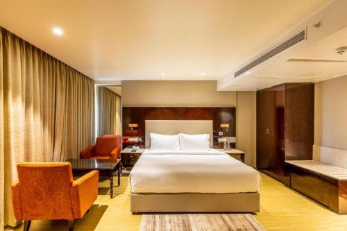 una camera d'albergo con letto e sedia di Citadel Sarovar Portico Bengaluru a Bangalore