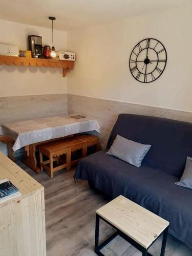 un salon avec un canapé et une horloge au mur dans l'établissement Appartement T2 , 4/5 couchages Station Risoul 1850, à Risoul