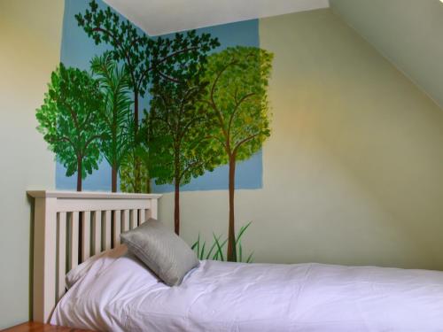 a bedroom with a mural of trees on the wall at Cobblers Cottage in Sawston