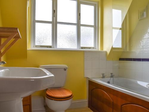 La salle de bains est pourvue de toilettes, d'un lavabo et d'une baignoire. dans l'établissement Cobblers Cottage, à Sawston