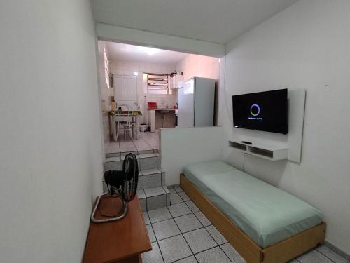 Cette petite chambre comprend un lit et une télévision murale. dans l'établissement Seu Apto na Praia da Costa 9 Simples e Barato Mobiliado Ar Cond Fogão TV Geladeira Local Excelente no Centro, à Vila Velha