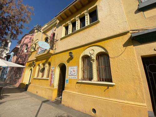 un edificio amarillo con ventanas en una calle en Hostal El Raco, en Santiago