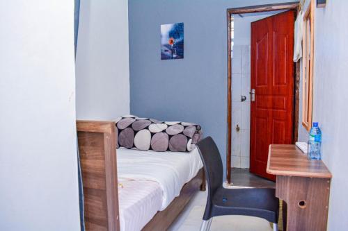 a small room with a bed and a desk and a red door at Dad's Place in Karatina