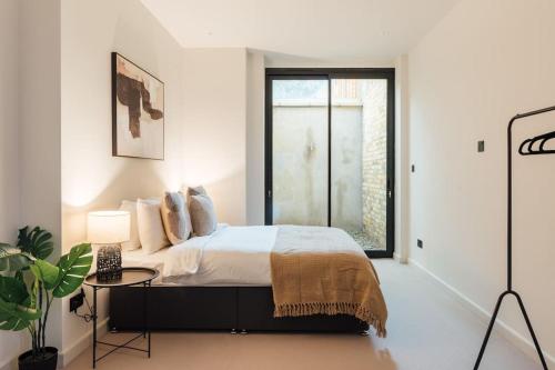 Luxurious & Modern London Apartment in Honor Oak في لندن: غرفة نوم بيضاء بها سرير ونافذة