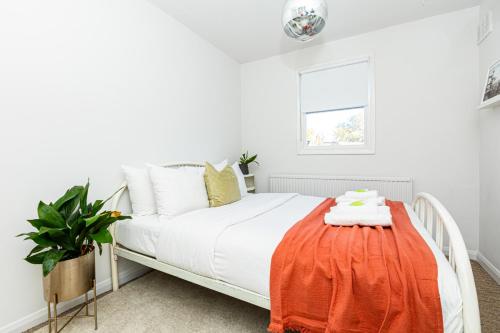 a bedroom with a white bed with an orange blanket on a table at Stunning 2BR Apt wPatio in Dalston, 2 min to Tube in London