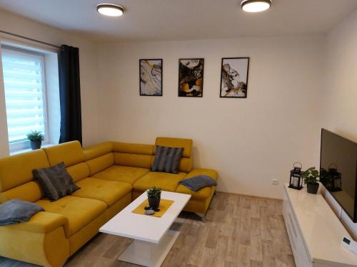 sala de estar con sofá amarillo y mesa en Apartmán Pod Bukem en Červená Voda