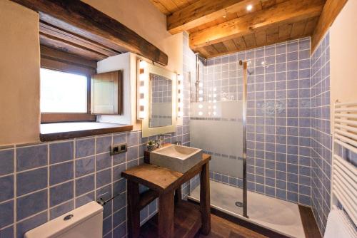 a blue tiled bathroom with a sink and a window at Egur Etxe I Caserío Vasco I Jardín I Porche I BBQ I Chimenea in Zárate