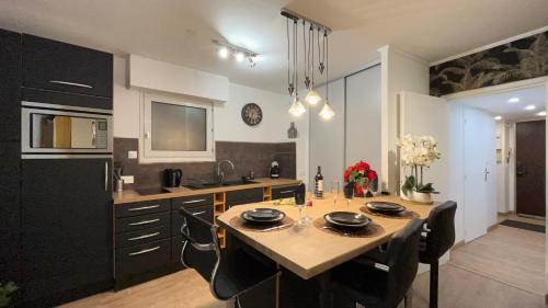 a kitchen with a table with black cabinets and a sink at Le Sainte Croix Hyper Centre Metz in Metz