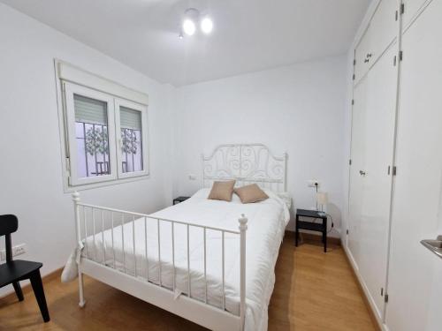 een witte slaapkamer met een wit bed en een raam bij CDZ - San Telmo, apartamentos con terraza in Cádiz