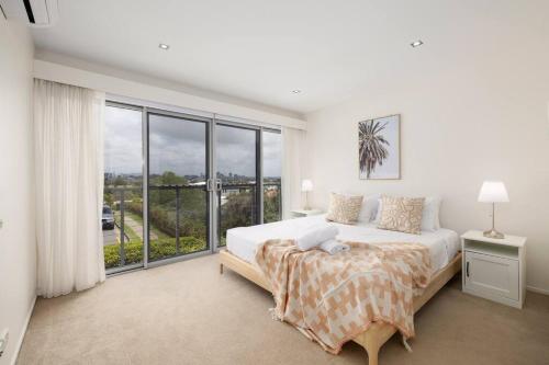 a white bedroom with a bed and a large window at Renov Peaceful 3BR Morningside Gem: Cozy Retreat in Brisbane