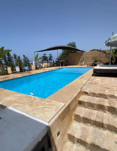 a swimming pool with stairs next to a house at LES OLIVIERS Villa N1 avec piscine privée in Oualidia