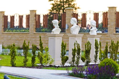 a row of white statues in front of a fence at Hotel Coloseum in Jarosław