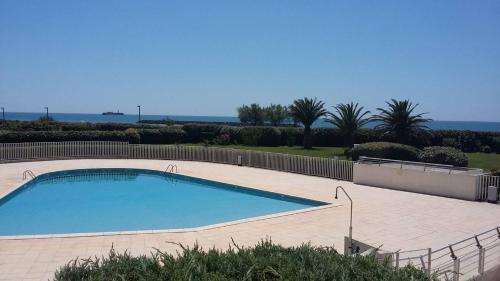 - une piscine dans une cour avec l'océan en arrière-plan dans l'établissement 3 pièces avec grande terrasse vue mer Rochelongue Cap d'Agde, au Cap d'Agde