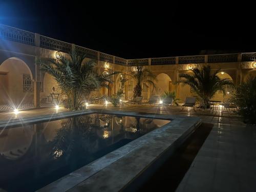 a building with a swimming pool at night at Riad Akabar Merzouga in Merzouga