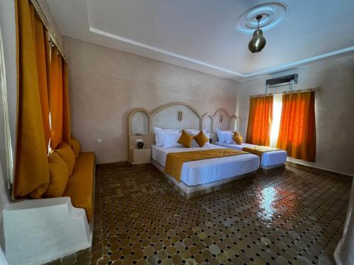 a bedroom with two beds and orange curtains at Riad Akabar Merzouga in Merzouga