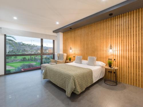 ein Schlafzimmer mit einem Bett und einem großen Fenster in der Unterkunft Salobre Golf Villas Tabaibas in Salobre